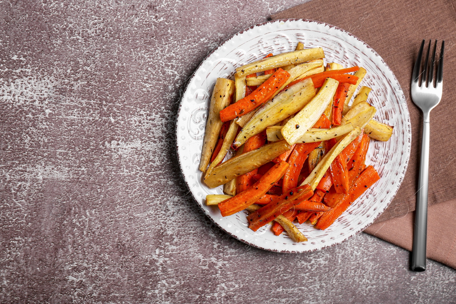 Photo of Plate with tasty parsnip and bell pepper served on brown textured table, flat lay. Space for text