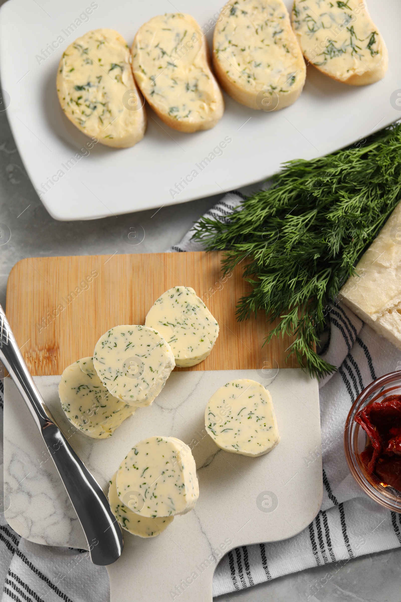 Photo of Tasty butter, dill, chili pepper and bread on table, top view