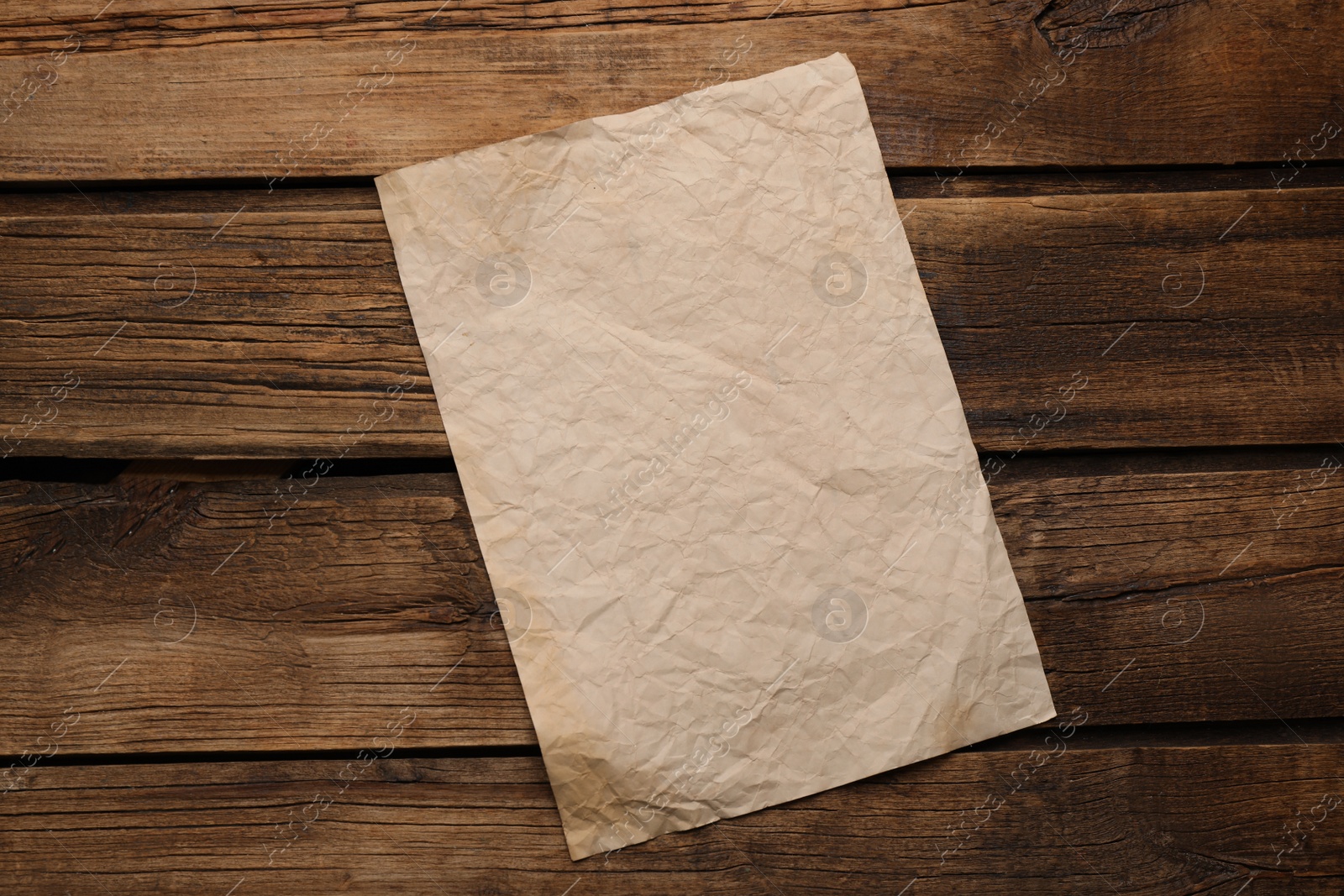 Photo of Sheet of old parchment paper on wooden table, top view. Space for design