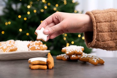 Photo of Woman with decorated Christmas cookies at table, closeup