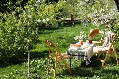 Photo of Beautiful table setting with spring flowers in garden on sunny day