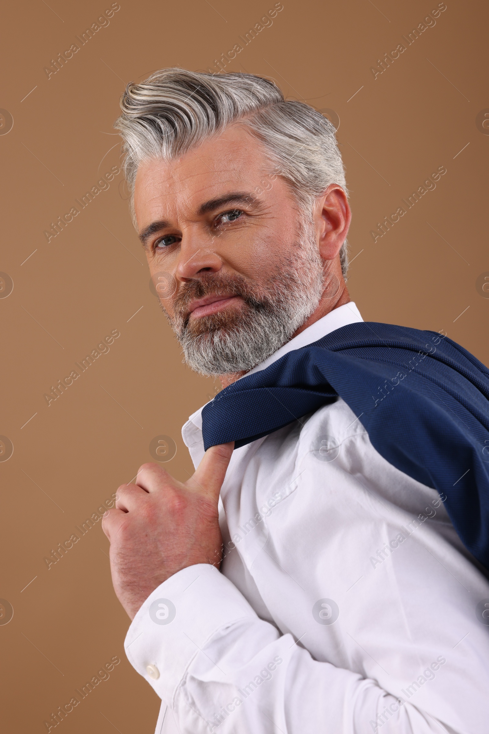 Photo of Portrait of confident man with beautiful hairstyle on light brown background