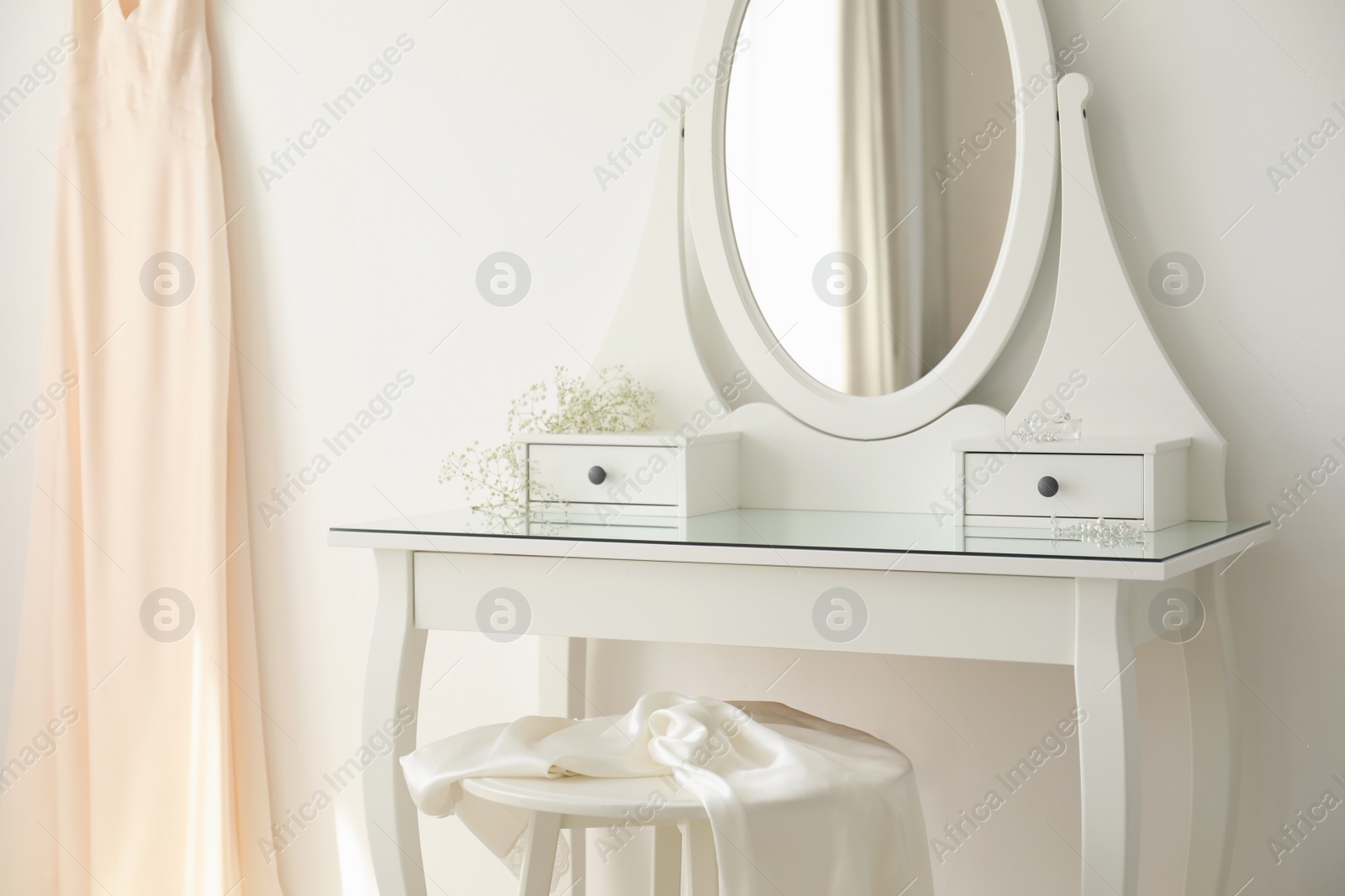 Photo of Beautiful wedding gown hanging near dressing table in room