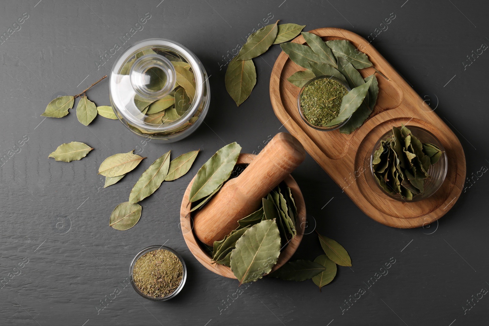 Photo of Whole and ground bay leaves on grey wooden table, flat lay