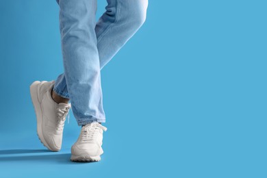 Photo of Man wearing stylish sneakers on light blue background, closeup. Space for text