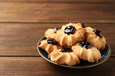 Photo of Tasty shortbread cookies with jam on wooden table