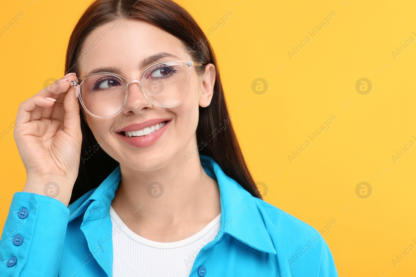Photo of Smiling woman in stylish eyeglasses on orange background. Space for text