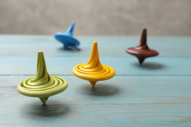 Photo of Bright spinning tops on light blue wooden table, closeup