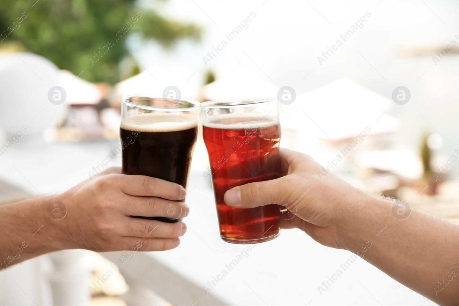 Photo of Friends clinking glasses with tasty beer outdoors