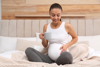 Happy pregnant woman drinking tea at home