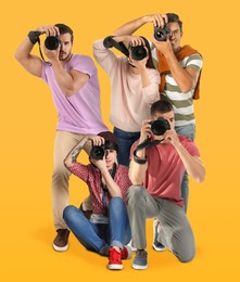 Image of Group of professional photographers with cameras on orange background