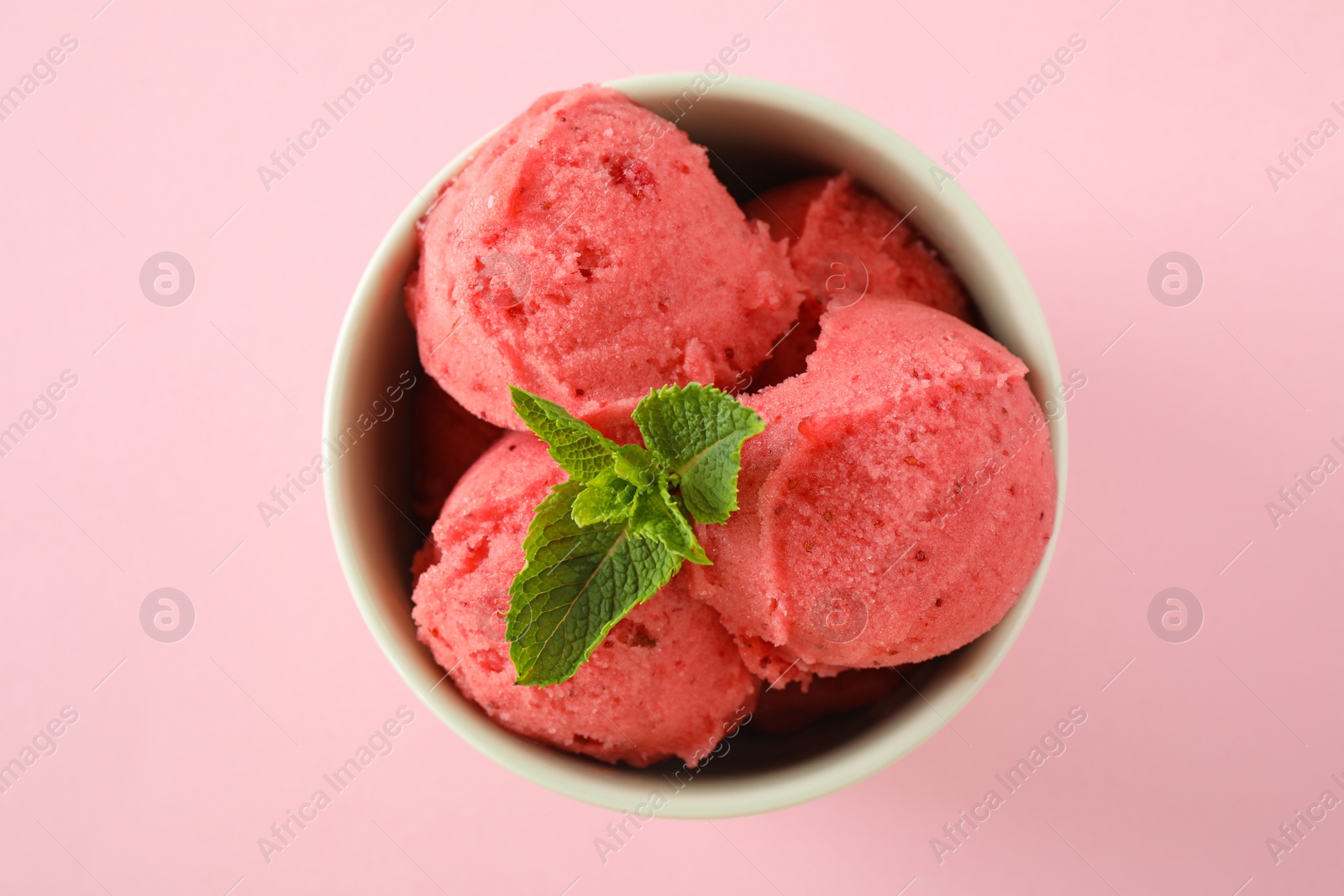 Photo of Delicious strawberry ice cream with mint in dessert bowl on pink background, top view