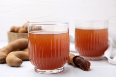 Photo of Tamarind juice and fresh fruits on white table, closeup