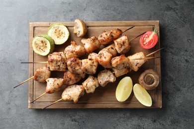 Photo of Delicious shish kebabs with vegetables and lemon on grey table, top view