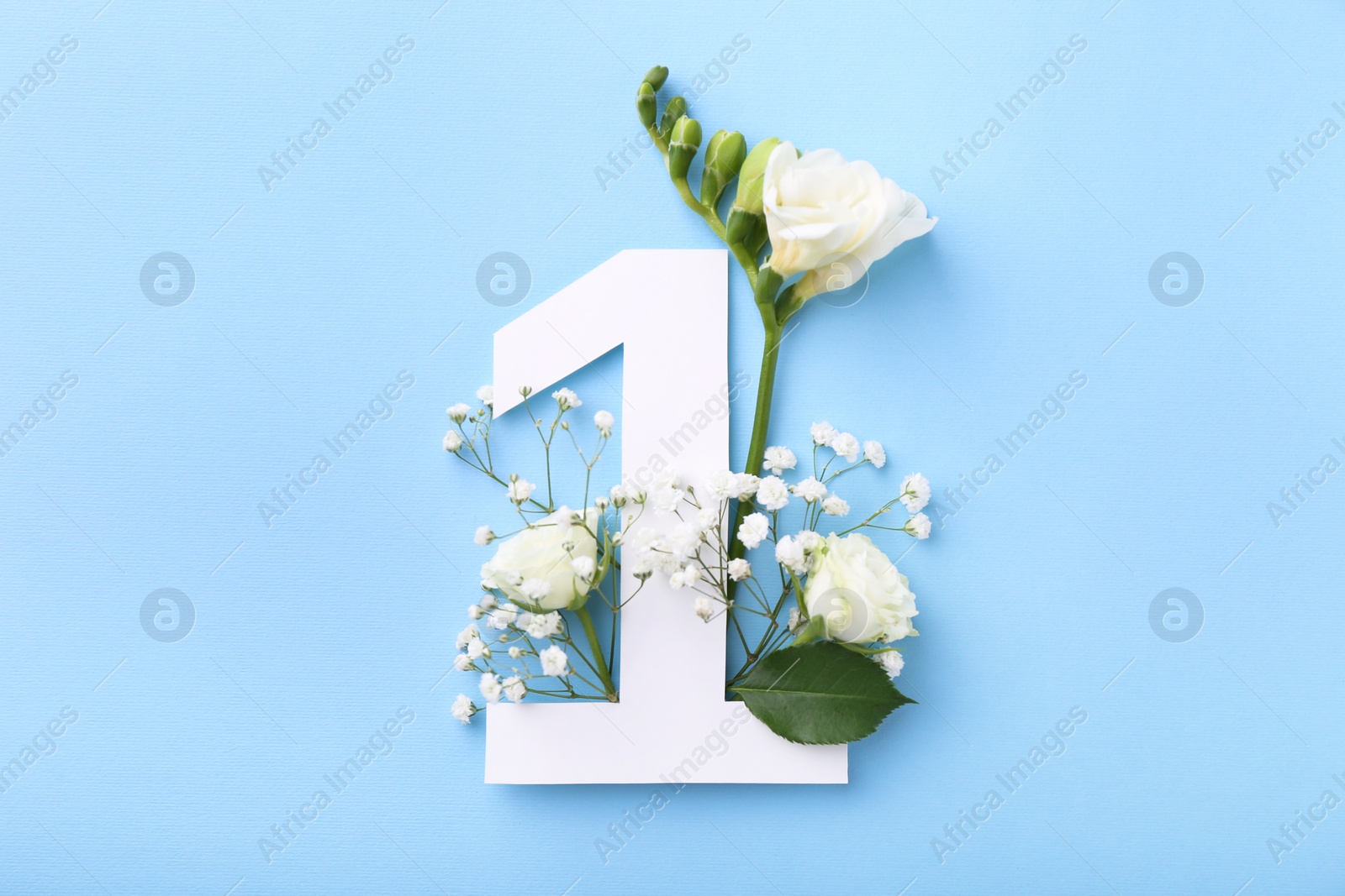 Photo of Paper number 1 and beautiful flowers on light blue background, top view