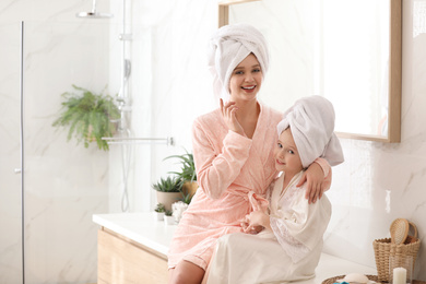 Happy mother and daughter near mirror in bathroom