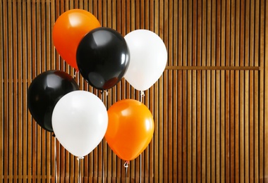 Photo of Colorful balloons against wooden wall, space for text. Halloween party