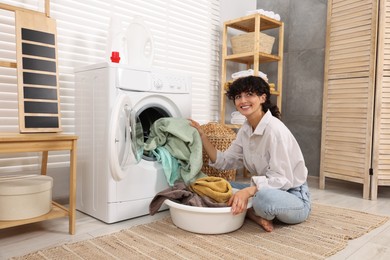 Woman taking laundry out of washing machine indoors