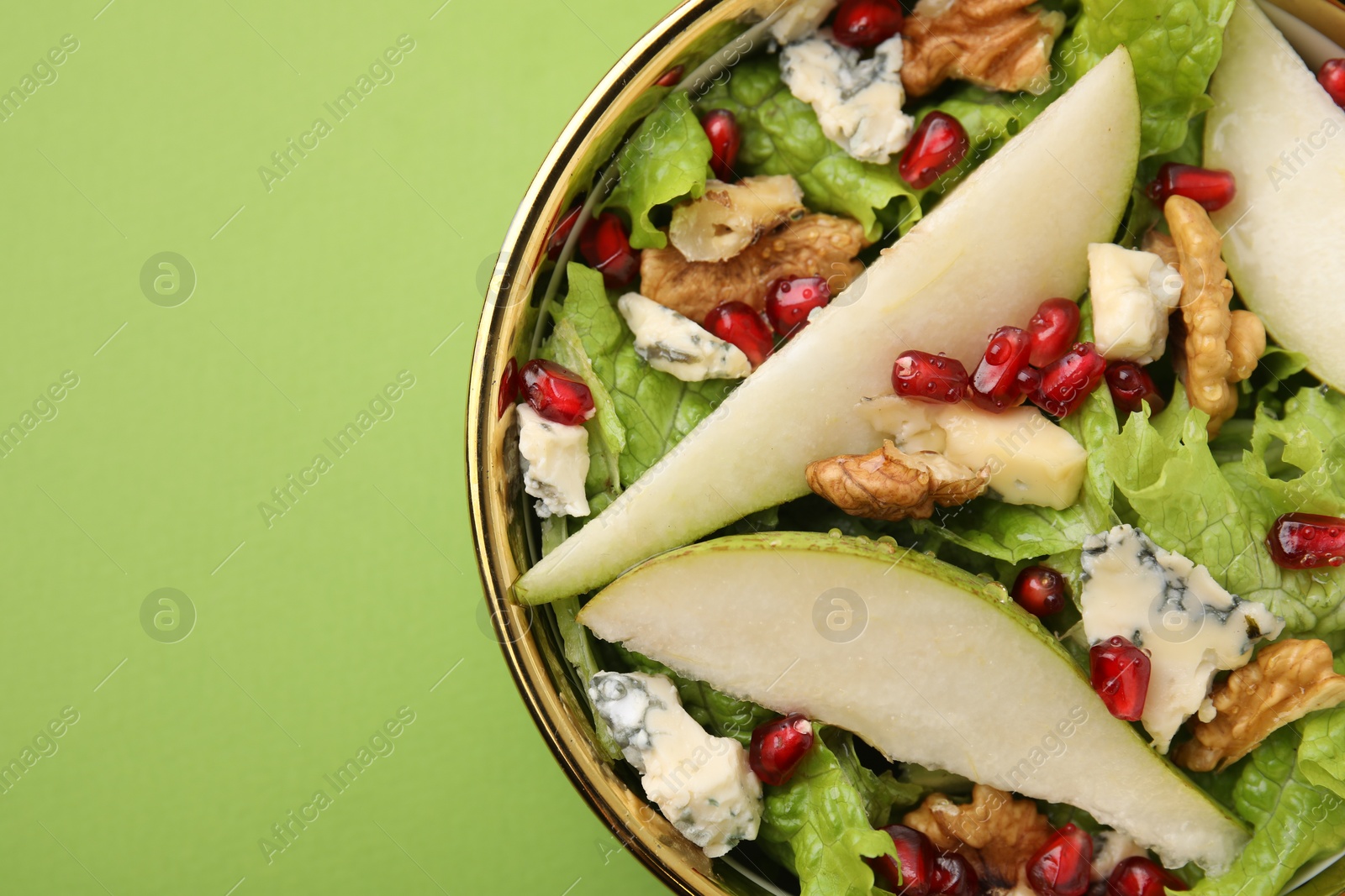 Photo of Delicious pear salad in bowl on green background, top view. Space for text