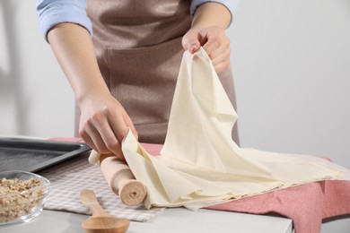 Photo of Making delicious baklava. Woman with dough at white table, closeup