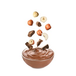 Image of Making yummy chocolate paste. Hazelnuts and pieces of chocolate falling into bowl on white background