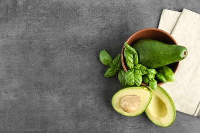 Flat lay composition with ripe avocados and basil on grey background