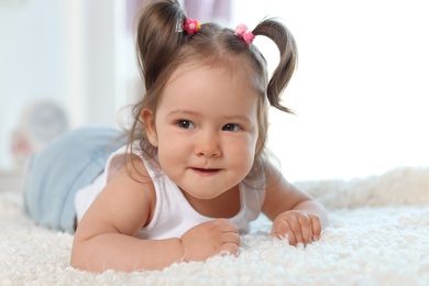 Photo of Adorable little baby girl lying on bed in room