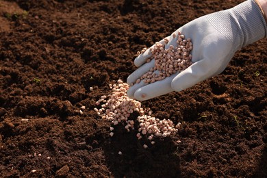 Photo of Man fertilizing soil, closeup. Space for text