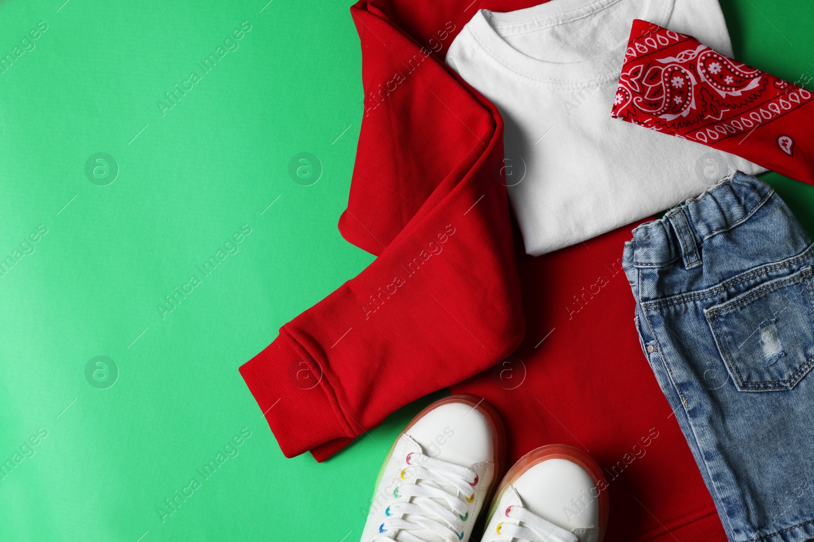 Photo of Stylish child clothes and shoes on green background, flat lay. Space for text