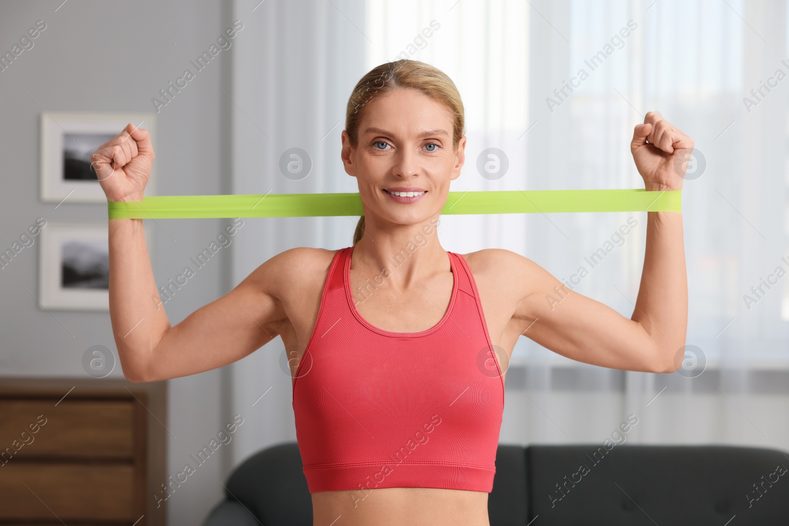 Photo of Athletic woman doing exercise with fitness elastic band at home