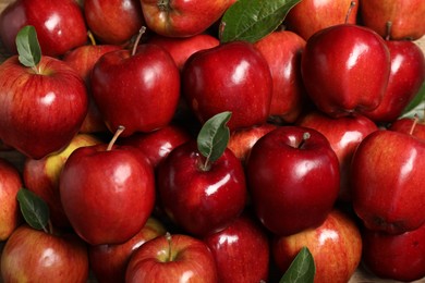 Photo of Fresh ripe red apples with leaves as background, closeup