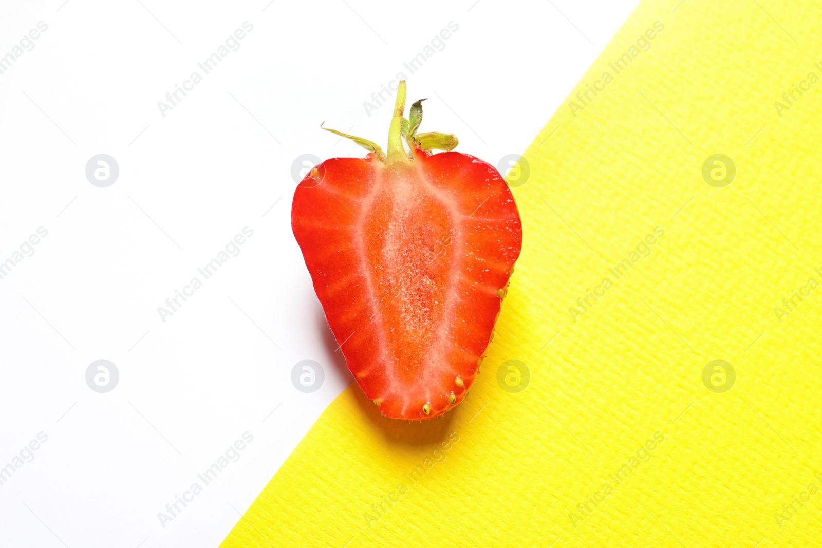 Photo of Half of ripe strawberry on color background, top view