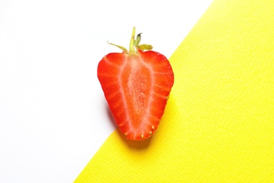 Half of ripe strawberry on color background, top view