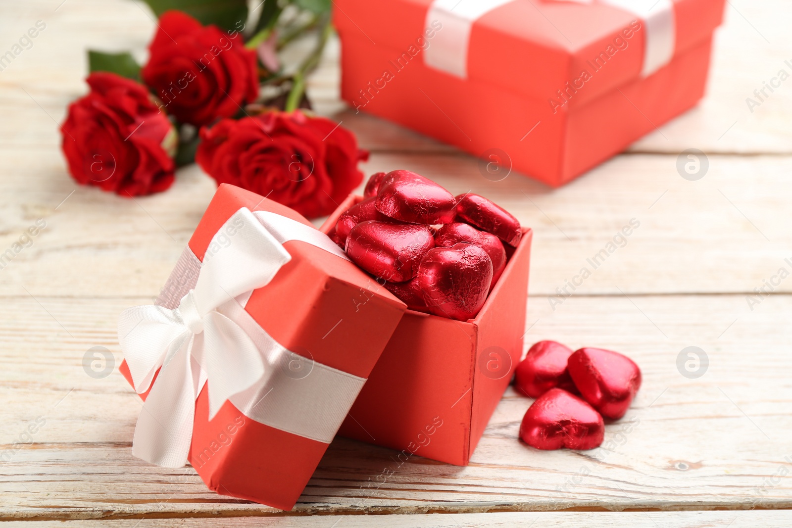 Photo of Heart shaped chocolate candies in box on white wooden table. Valentine's day celebration