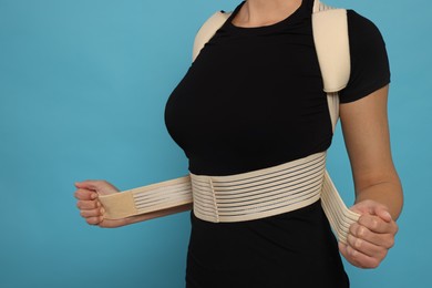 Closeup view of woman with orthopedic corset on blue background. Space for text