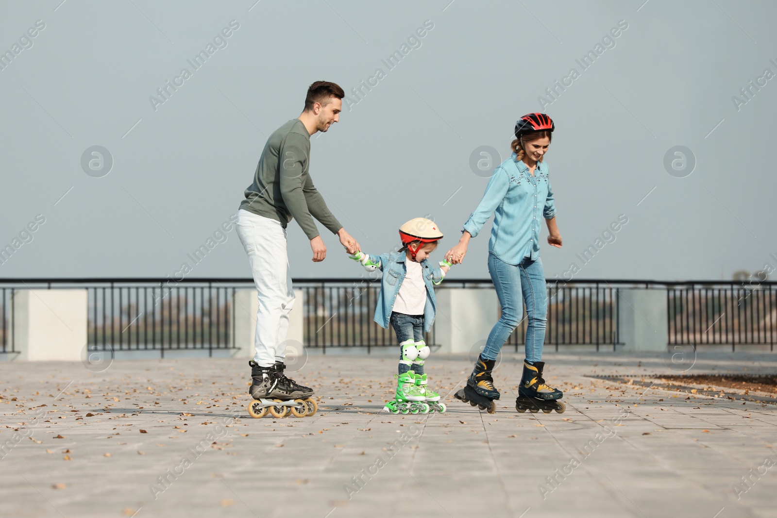 Photo of Happy family roller skating on embankment. Active leisure