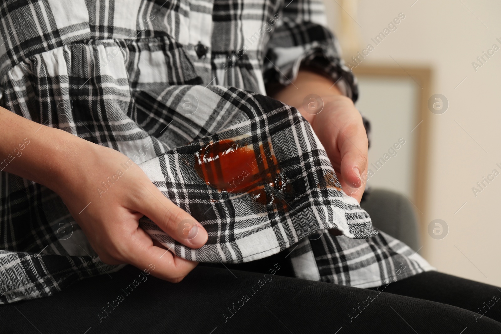 Photo of Woman showing sauce stain on her shirt indoors, closeup