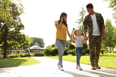 Photo of Man in military uniform and his family walking at sunny park