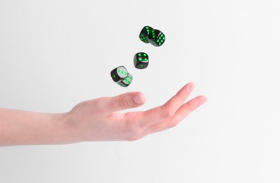 Photo of Woman throwing game dices on white background, closeup