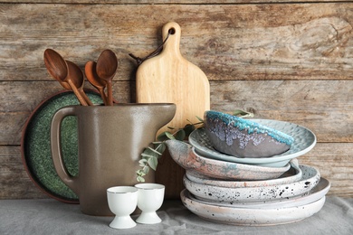 Photo of Composition with dishware and utensils on table against wooden background. Interior element