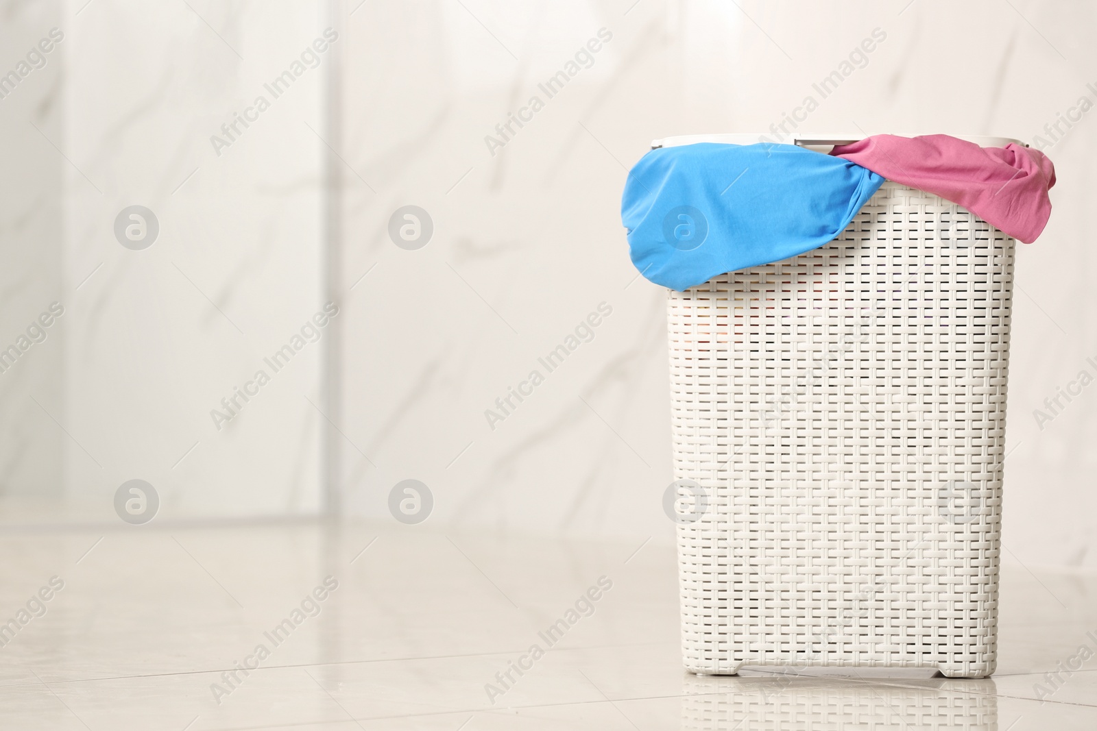 Photo of Laundry basket with dirty clothes on floor in room, space for text