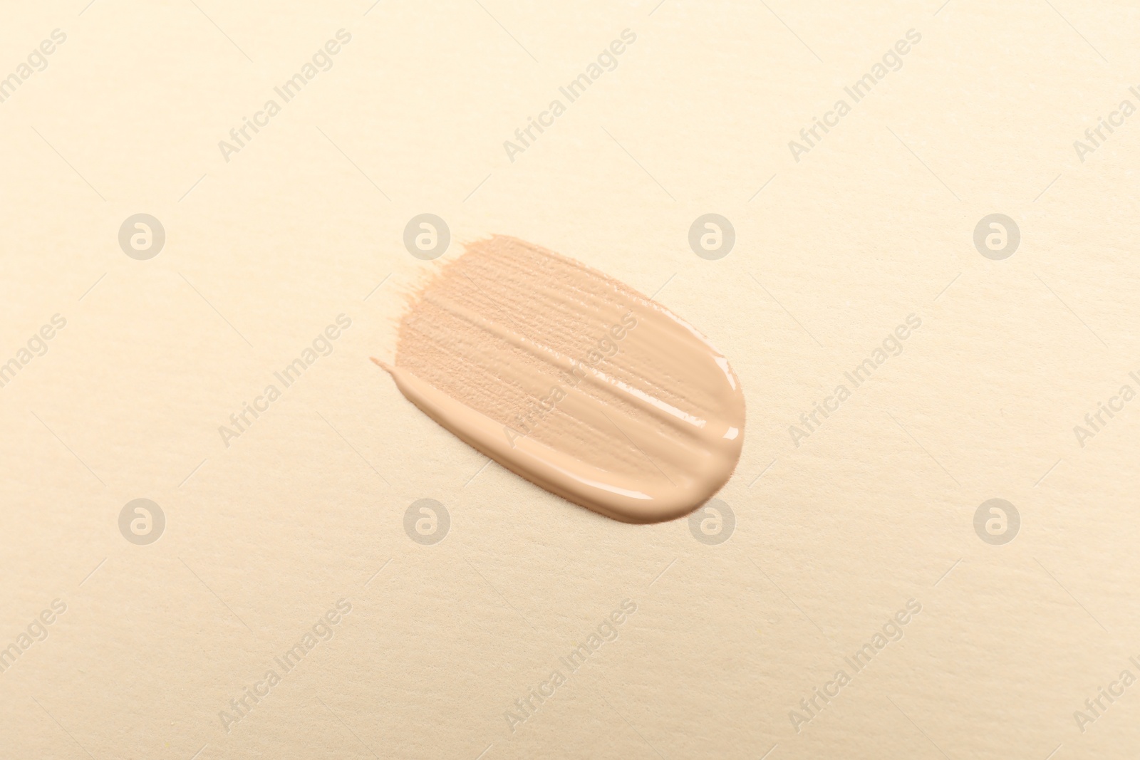 Photo of Smear of skin foundation on beige background, top view