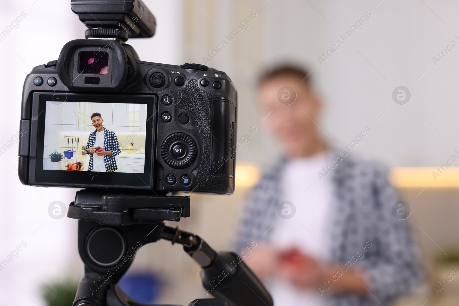 Photo of Food blogger recording video in kitchen, focus on camera