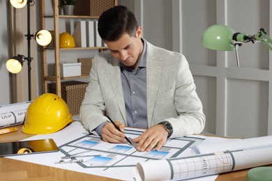 Photo of Architect working with construction drawings in office