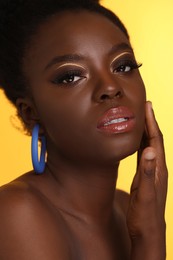 Photo of Fashionable portrait of beautiful woman with makeup on yellow background, closeup