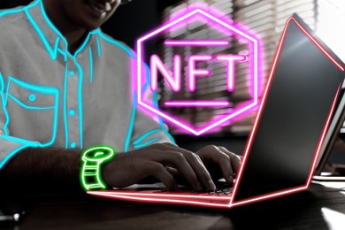 Image of Man using laptop at table, closeup. Abbreviation NFT (non-fungible token) over device. Neon outline effect