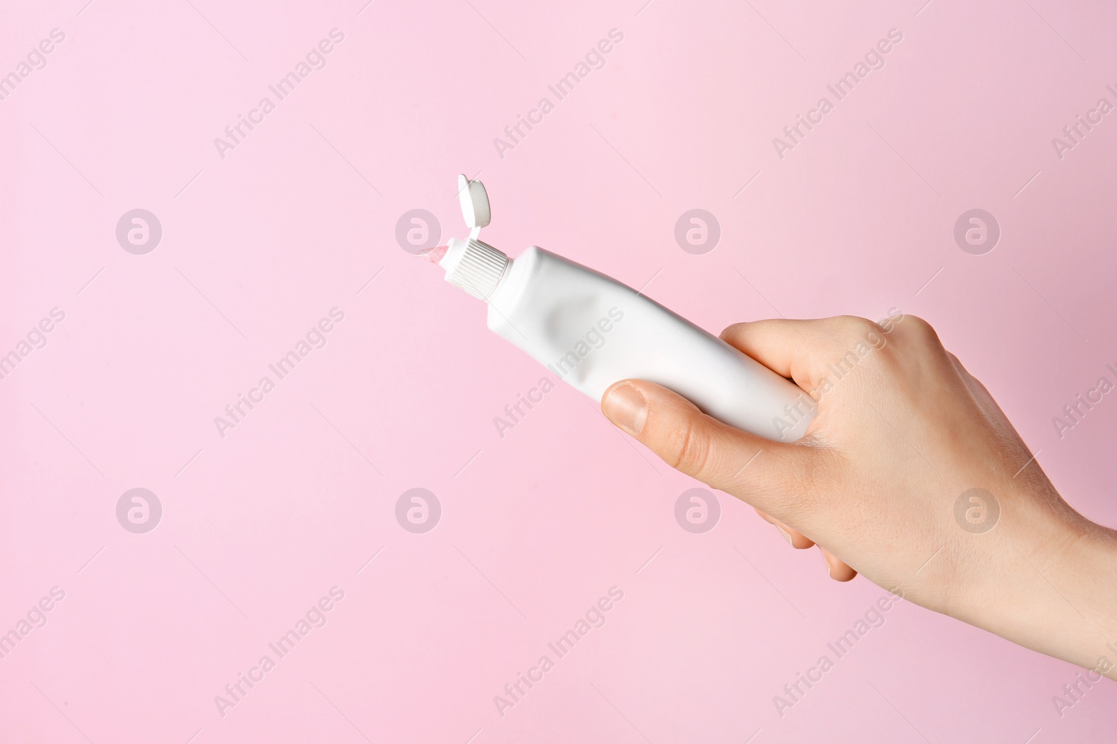 Photo of Woman holding tube of toothpaste on color background