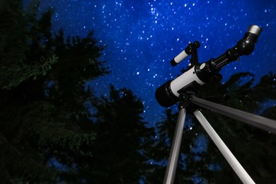 Photo of Modern telescope at night outdoors, low angle view. Learning astronomy