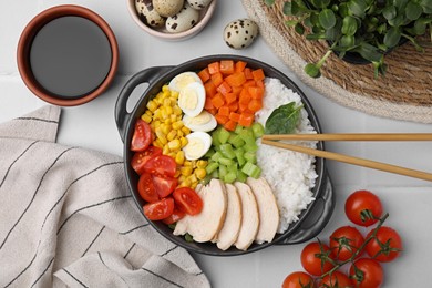 Photo of Delicious poke bowl with different ingredients, chopsticks and soy sauce on white table, flat lay