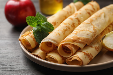 Photo of Delicious rolled  thin pancakes on wooden table, closeup
